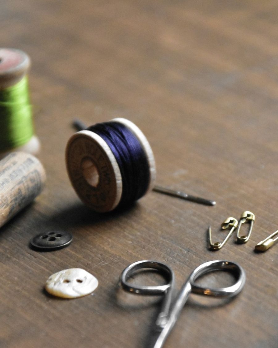 Thread spools, buttons and scissors on a wooden worktable