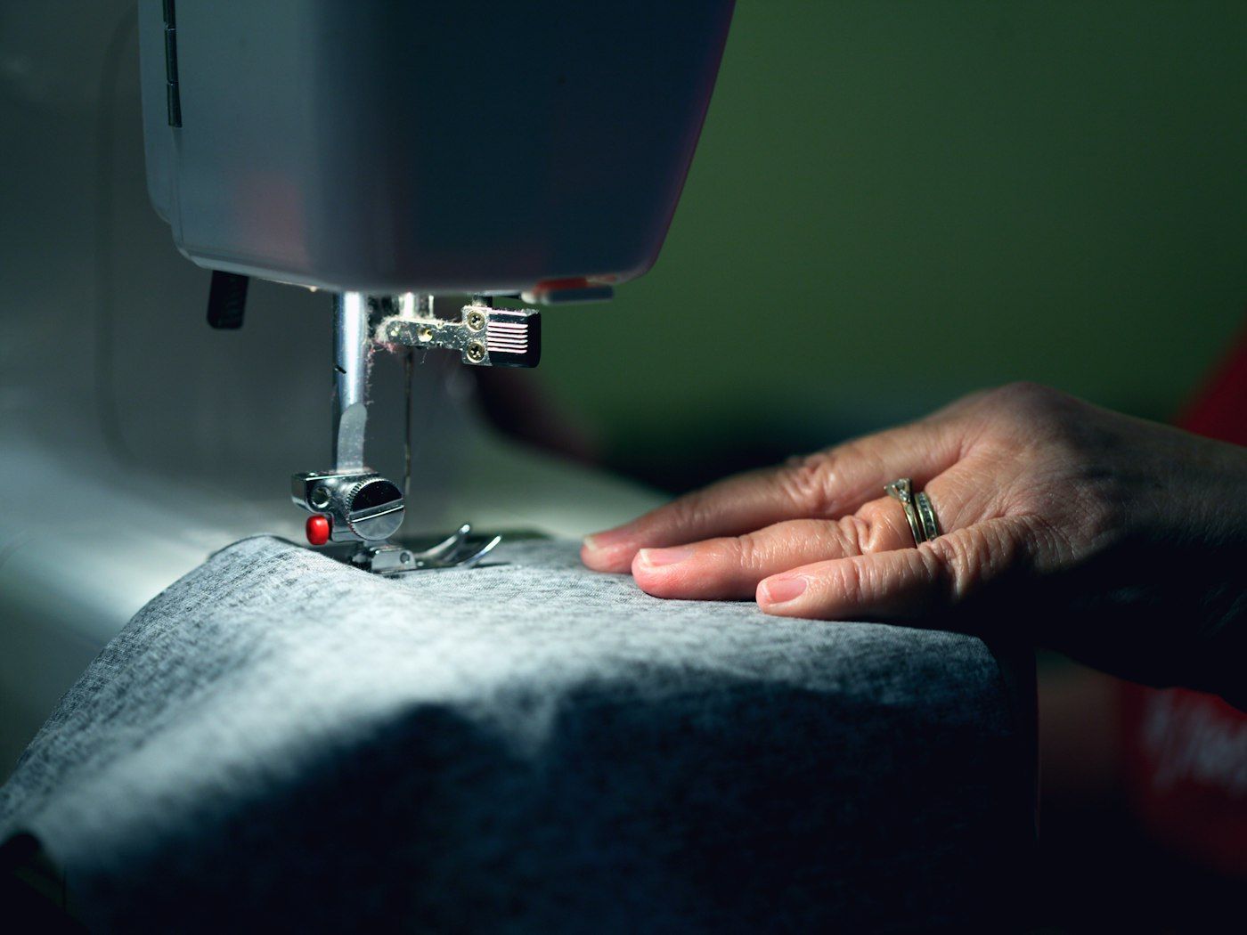 Close-up of hands guiding fabric under a sewing machine needle